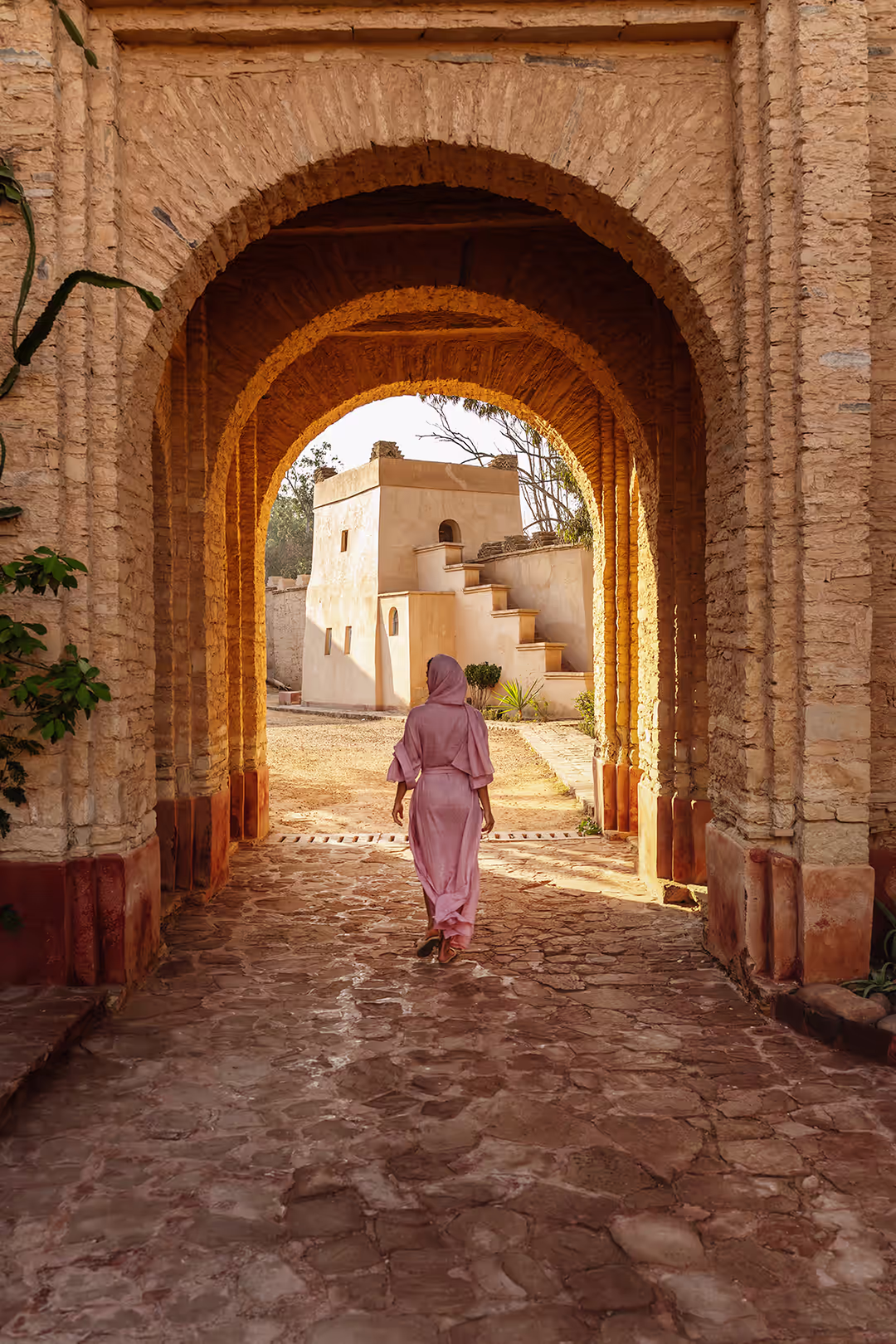 Viajera cruzando la entrada en arco de un edificio tradicional marroquí