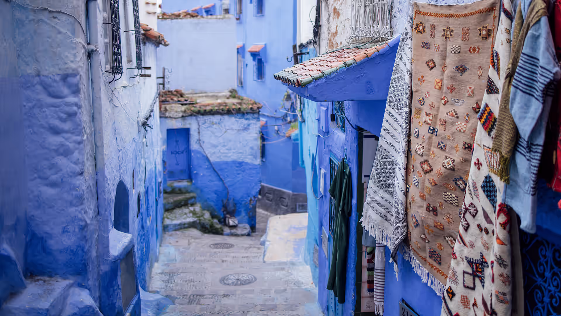 Calle estrecha azul de Chefchaouen decorada con macetas de colores