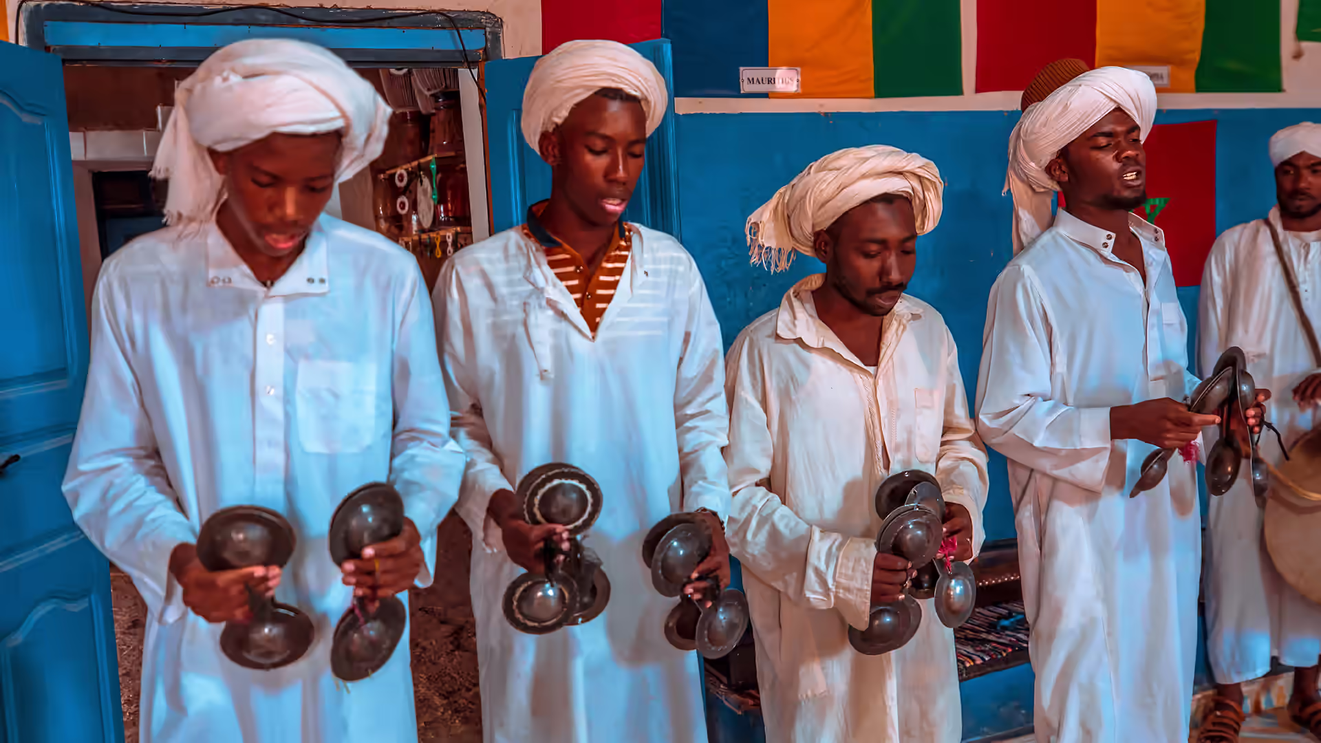 Fila de músicos gnawa con krakebs metálicos en una casa de Khamlia